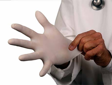 Arzt zieht sich einen Handschuh an